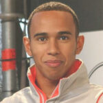 En man i ett grått jack och vit skjorta står bredvid en bil. (AI text)