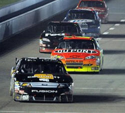 NASCAR-bilar tävlar under nattetid. (AI text)