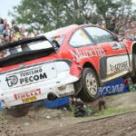 En rallybil hoppas över en grusväg. (AI text)