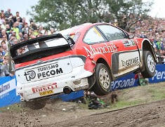 En rallybil hoppas över en grusväg. (AI text)