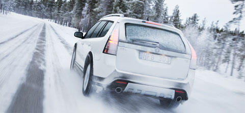 En vit bil körer nerför en snöig väg. (AI text)