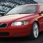 En röd Volvo S60 kör på en väg. (AI text)