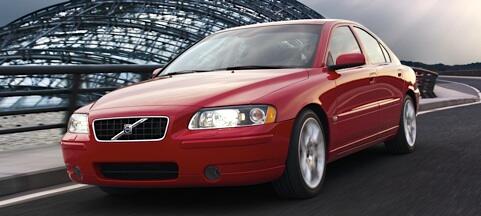 En röd Volvo S60 kör på en väg. (AI text)