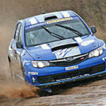 En blå Subaru WRX STI kör på en smutsig bana. (AI text)