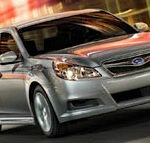 En silver Subaru Saturn kör nedför en stadsgata. (AI text)