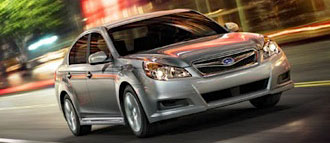 En silver Subaru Saturn kör nedför en stadsgata. (AI text)