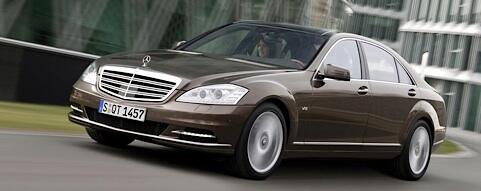 En Mercedes S-class sedan kör på en stadsgata. (AI text)
