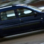 En blå bil kör nerför en snöig väg. (AI text)