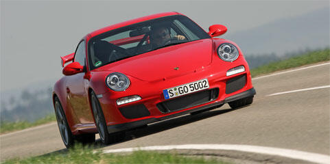 En röd Porsche 911 GTS kör längs en väg. (AI text)