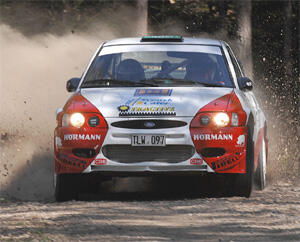 En rallybil kör genom ett skogsparti. (AI text)