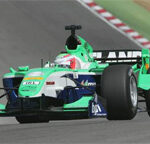 En grön formelbil kör nerför banan. (AI text)