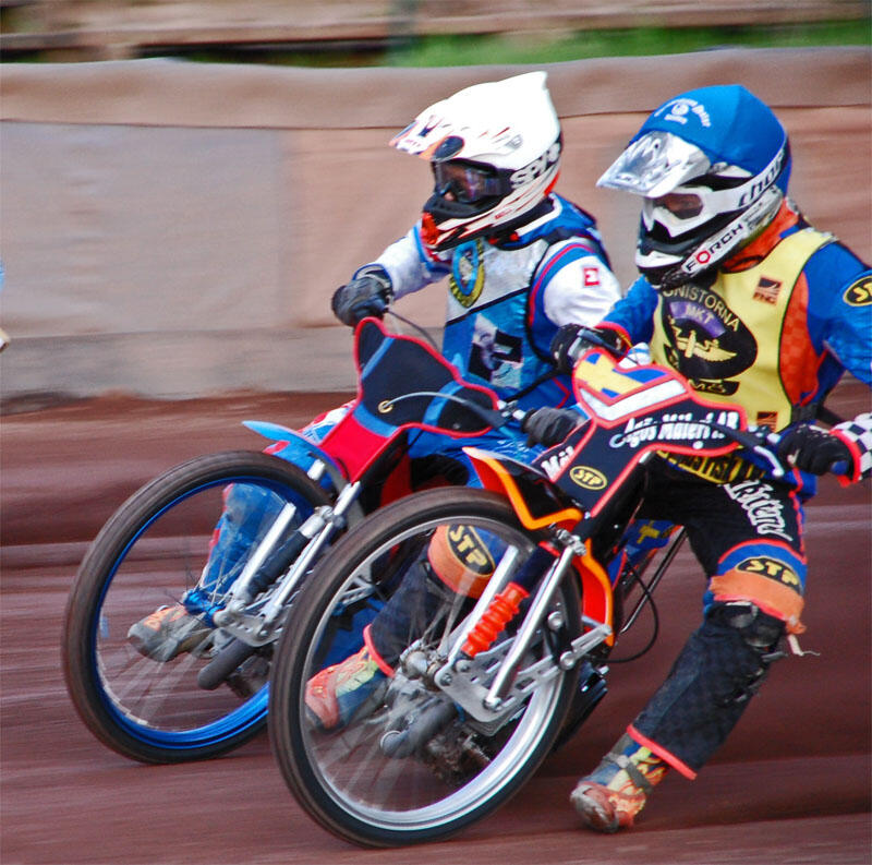 En motorcykeltävling och en motorcykelförare på en grusbana. (AI text)