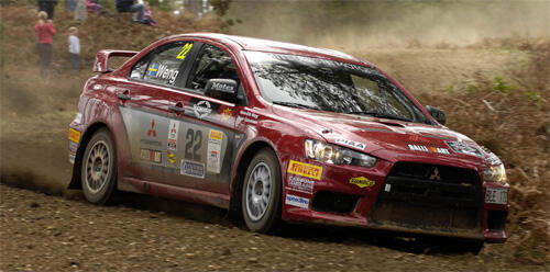 En röd rallybil kör på en grusväg. (AI text)