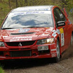 En röd rallybil kör nedför en grusväg. (AI text)