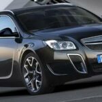 En Opel Insignia, en svart bil, parkerad framför ett byggnad. (AI text)