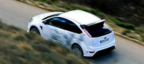 En vit Ford Focus RS kör nerför en bergsväg. (AI text)