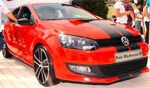 En röd Volkswagen Polo GTI parkerad framför en skara folk. (AI text)