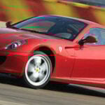 En röd Ferrari-sportbil kör på en bana. (AI text)