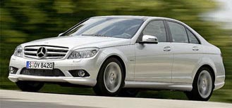 En Mercedes C-klass sedan kör nedför vägen. (AI text)
