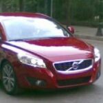 En röd Volvo C40 kör ner en gata. (AI text)