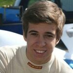 En ung man leker till synes inför en racingbil. (AI text)