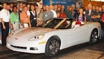 En grupp personer står omkring en vit cabriolet Chevrolet Corvette. (AI text)
