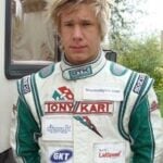 En ung man i en raceklädsel står bredvid en trailer. (AI text)