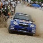 En rallybil körer längs en grusväg. (AI text)