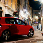 En röd Volkswagen Golf parkerad på en stadsgata. (AI text)