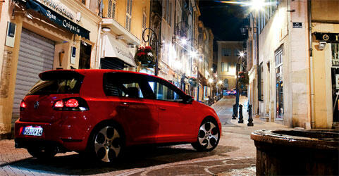 En röd Volkswagen Golf parkerad på en stadsgata. (AI text)