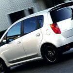 En vit bil kör nerför en gata. (AI text)