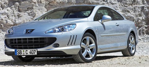 En silverfärgad Peugeot parkerad framför en bergsklädd bergsrygg. (AI text)