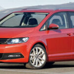 En röd Volkswagen Touran parkerad vid vägkanten. (AI text)