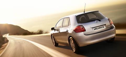 En silverfärgad bil kör nerför en väg. (AI text)