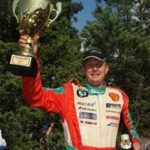 En racerförare håller upp en pokal. (AI text)