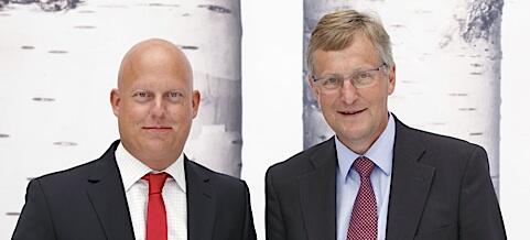 En man i kostym och slips står bredvid en bil. (AI text)