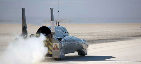 En racebil kör längs en ökenväg. (AI text)