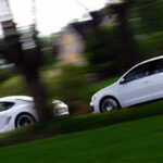 En vit Volkswagen Golf GTI kör nedför en väg. (AI text)