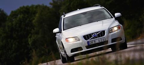 En vit Volvo V60 vagn kör ner en väg. (AI text)