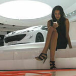 En kvinna sitter på en bil på bilsalongen. (AI text)