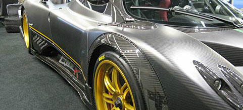 En grå sportbil med gula hjul utställd på en bilsalong. (AI text)