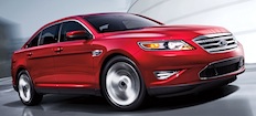 En röd Ford Taurus körs nedför en gata. (AI text)