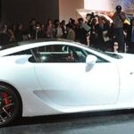 En vit sportbil visas på en bilsalong. (AI text)