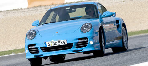 En blå Porsche 911 GTS kör på en racebana. (AI text)