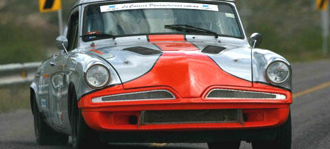 En klassisk bil kör nedför en väg. (AI text)