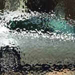 En bil körer nedför en gata på en regnig dag. (AI text)