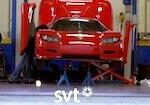 En röd sportbil repareras i ett garage. (AI text)