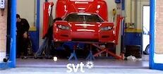 En röd sportbil repareras i ett garage. (AI text)