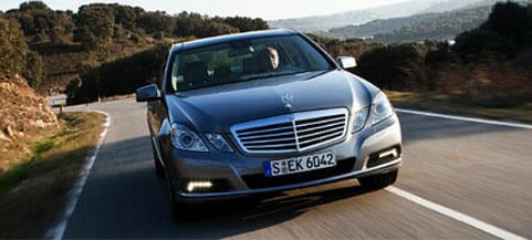 En Mercedes-Benz E-klass kör nedför en landsväg. (AI text)