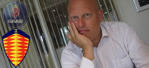 En man i skjorta och slips sitter vid ett skrivbord. (AI text)